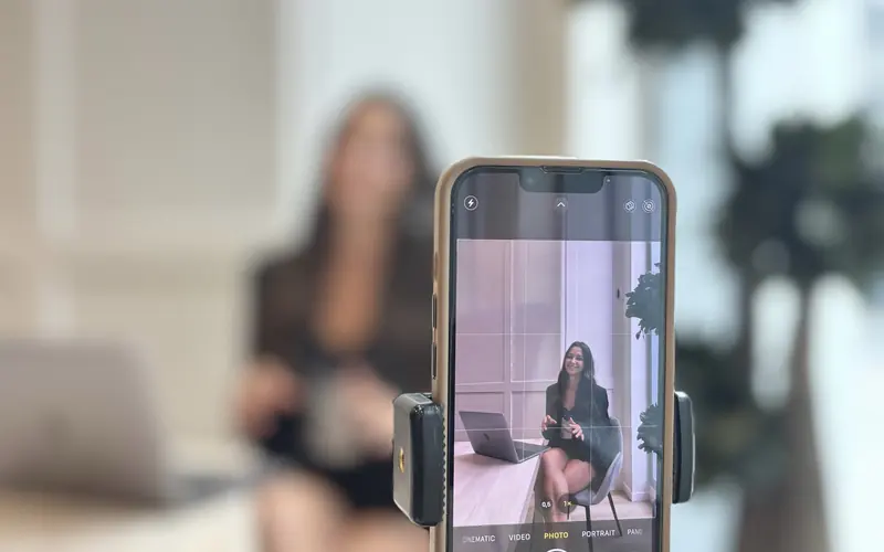 Perempuan merekam dirinya dengan ponsel yang dipasang pada tripod